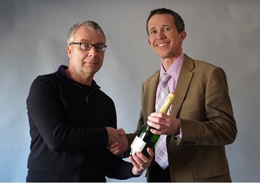 Photo of Michael Hinett presenting champagne to David Morphew